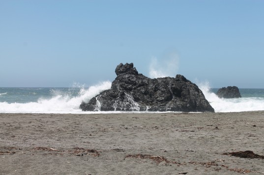 Waves crashing over a boulder on the Sonoma Coast
